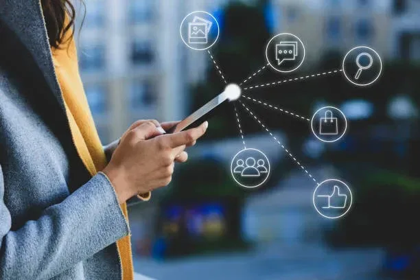Mobile First: Navigating Digital Touchpoints "Person holding a smartphone with interconnected white digital icons representing social media, chat, search, shopping, and community engagement."